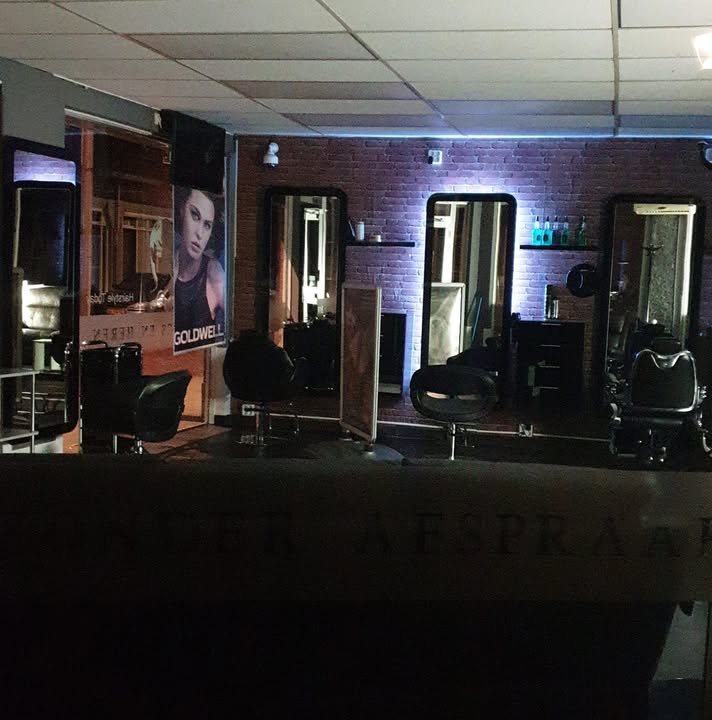De salon van Hairstyle Today in de avond, met verlichte spiegels en de kappersstoelen